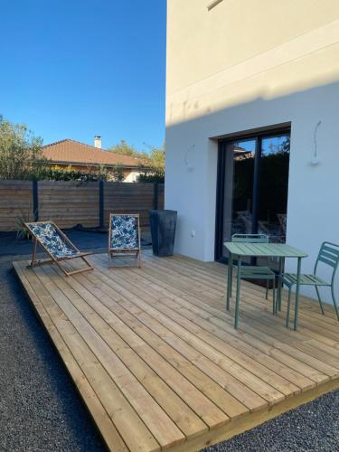 eine Holzterrasse mit einem Tisch und Stühlen darauf in der Unterkunft Charmant studio entre bassin et océan in Lège-Cap-Ferret