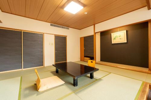 a room with a table and a chair and windows at Ooedo Onsen Monogatari Higashiyama Grand Hotel in Aizuwakamatsu