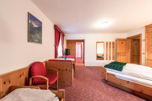 um quarto de hotel com uma cama e uma cadeira em Hotel Savoia em Canazei