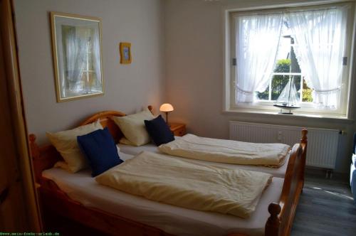 two twin beds in a bedroom with a window at Haus 94- Whg EG in Oldsum