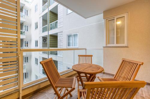 uma varanda com 3 cadeiras e uma mesa de madeira em A beautiful, brand new 2BR home in St Pauls by 360 Estates em St. Paul's Bay