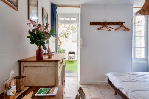 - une chambre avec un lit et une table fleurie dans l'établissement La Suite 24 - Studio avec Terrasse à 100m du port de Saint-Martin-de-Ré, à Saint-Martin-de-Ré