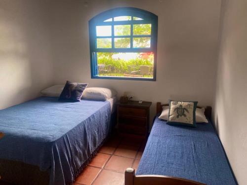 a bedroom with two beds and a window at Suítes Pé na Areia in Barra do Sahy