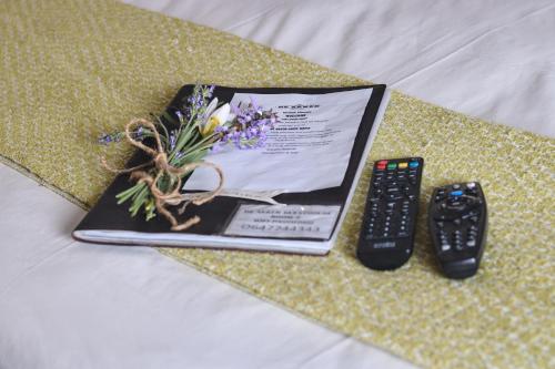 a book with a bouquet of flowers next to a remote control at De Akker Guest House Oudtshoorn in Oudtshoorn