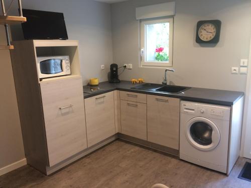 a kitchen with a washing machine and a microwave at Les gîtes de Joséphine proche Chambord in Courbouzon