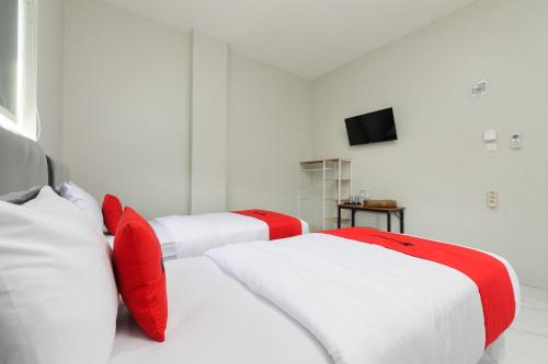 two white beds with red pillows in a room at RedDoorz near GSG UNILA Lampung in Hajimana