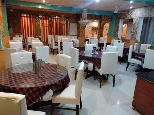 uma sala de jantar com mesas e cadeiras brancas em Hotel Star of Kashmir em Srinagar