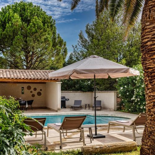 a patio with an umbrella and chairs and a pool at Maison Belleviste in Maillane