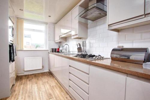 a kitchen with white cabinets and a counter top at Beautiful House Sleeps 6 - Manchester in Manchester