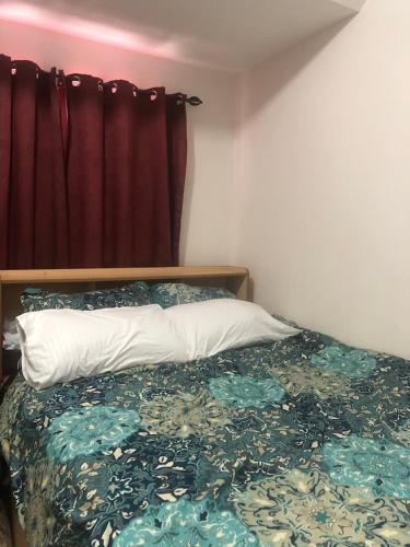 ein Schlafzimmer mit einem Bett mit einer Bettdecke und einem Fenster in der Unterkunft Amenadiel & CC - Imus Staycation in Imus