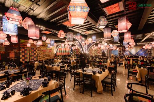 Lan Rung Brocade Hotel في سابا: غرفة طعام مع طاولات وكراسي وأضواء صينية
