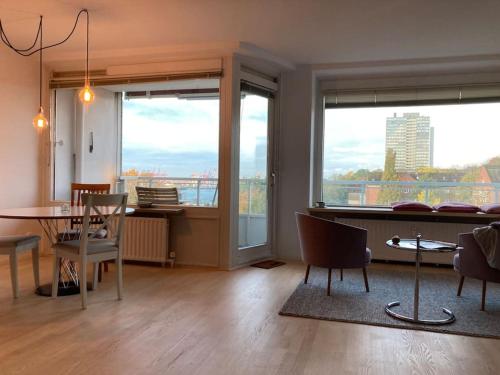 ein Wohnzimmer mit einem Tisch, Stühlen und Fenstern in der Unterkunft River View Apartment in Hamburg