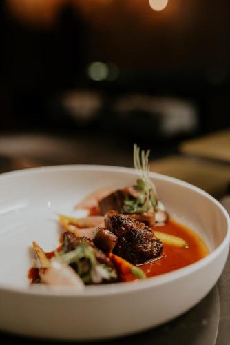 a white bowl of soup with meat and vegetables at Kozmo Hotel Suites & Spa - Small Luxury Hotels of the World in Budapest