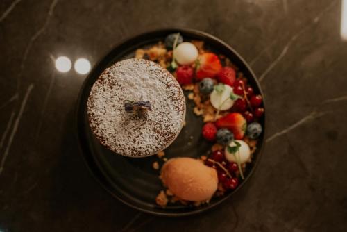 a plate of food with fruit on a table at Kozmo Hotel Suites & Spa - Small Luxury Hotels of the World in Budapest