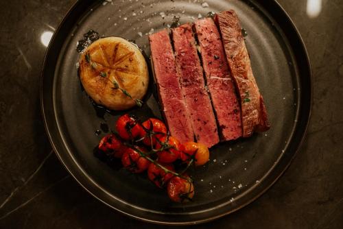a plate of food with meat and fruit on it at Kozmo Hotel Suites & Spa - Small Luxury Hotels of the World in Budapest