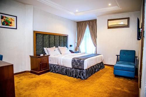 a hotel room with a bed and a blue chair at Fritz Apartments & Suites in Abuja