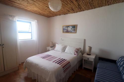 a bedroom with a white bed and a window at Dyers House Kassiesbaai Arniston in Arniston