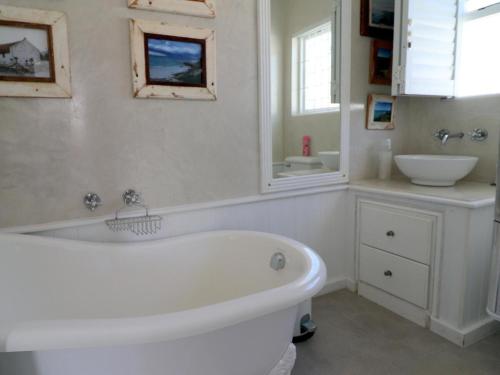 a white bathroom with a tub and a sink at Eland's Rest In Arniston in Arniston