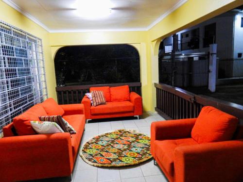 a living room with orange furniture and a large window at Yaubula Accommodation 2 in Nadi
