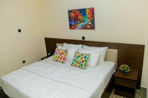 a bedroom with a bed with white sheets and pillows at Fragrance Apartments and Suites in Ibadan