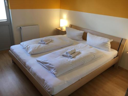 a large white bed with two slippers on it at Mueritz-Ferienhaus-Wiesenblick-|-Garten-Sauna-Kamin-und-Boot-|-200-Meter-zur-Mueritz in Marienfelde