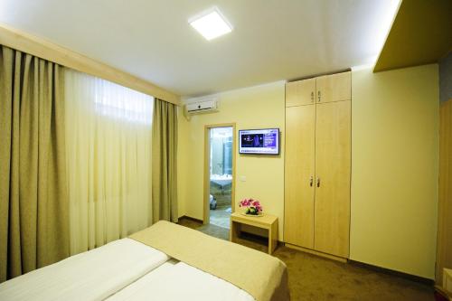 a bedroom with a bed and a tv on the wall at Pensiunea President City in Roşiori de Vede