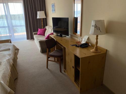 a hotel room with a desk with a television and a bed at Eva in Mrągowo