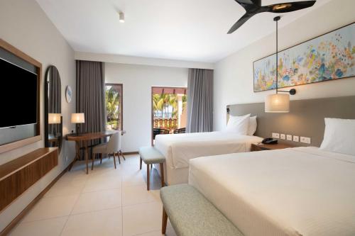 a hotel room with two beds and a television at Hilton Mauritius Resort & Spa in Flic-en-Flac