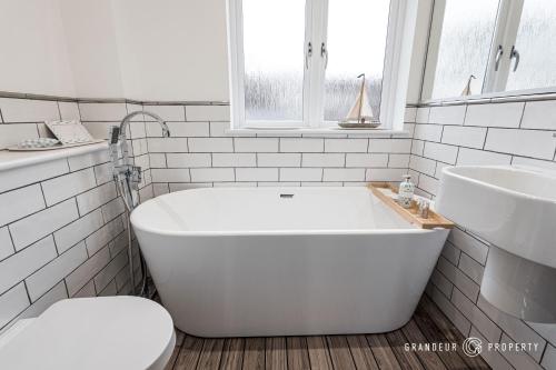 uma casa de banho branca com uma banheira e um lavatório em Tranquil 3-Bedroom Haven in Lymington - The Herons Nest em Lymington