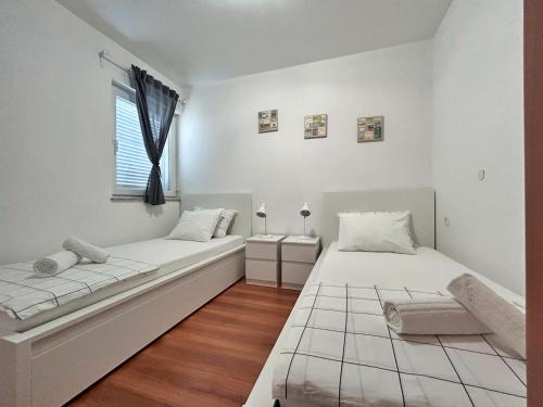 2 łóżka w białym pokoju z oknem w obiekcie Apartments Pinta de Sol w mieście Čižići