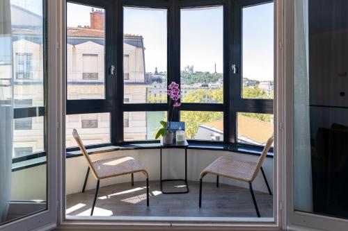 two chairs and a table in a room with windows at Best Western Hotel du Pont Wilson in Lyon