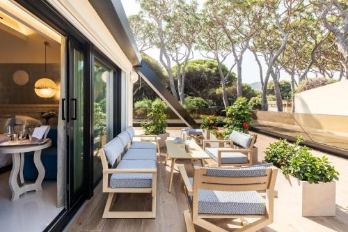 an outdoor patio with tables and chairs and trees at Cala Beach Resort in Punta Ala