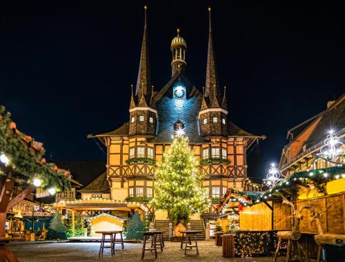 a christmas tree in front of a building with a clock tower at FeWo Wanderlust #Innenstadt#Außenbereich#ruhige Lage von Harztraveler in Wernigerode
