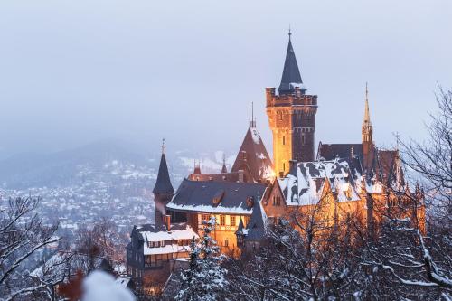 a large castle with a clock tower in the snow at FeWo Wanderlust #Innenstadt#Außenbereich#ruhige Lage von Harztraveler in Wernigerode