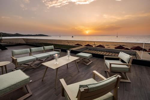 a patio with tables and chairs on the beach at Cala Beach Resort in Punta Ala