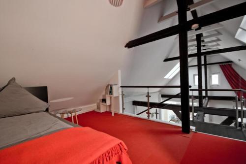 a bedroom with a red bed and a staircase at Packhaus Norderney in Norderney