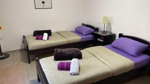 three beds in a room with purple and purple pillows at Dody Apartmani in Leskovac
