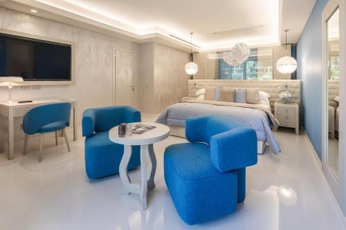 a bedroom with a bed and two blue chairs at Cala Beach Resort in Punta Ala