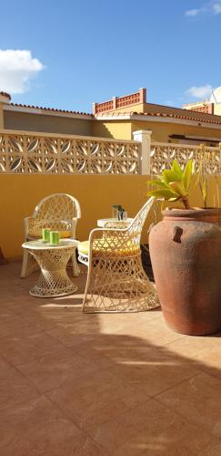 un patio con sedie, tavolo e piante in vaso di Villa Ghìo a Caleta De Fuste