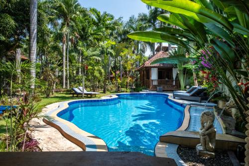 a pool in a backyard with palm trees and a house at Lombok Stanley Garden Villas in Montongbuwoh