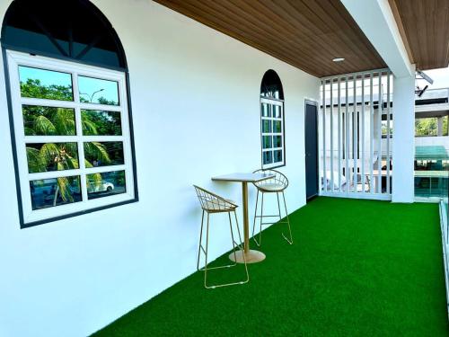 Habitación con alfombra verde, mesa y sillas en Three Homestay, en Perai
