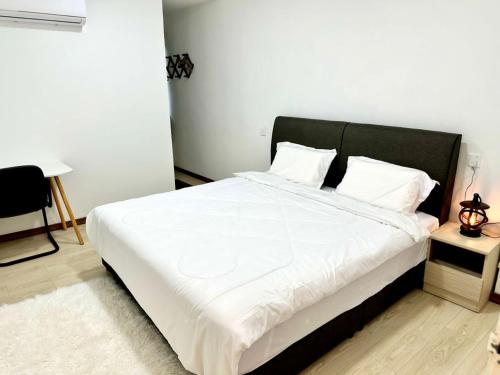 a bedroom with a large white bed with a black headboard at Three Homestay in Perai