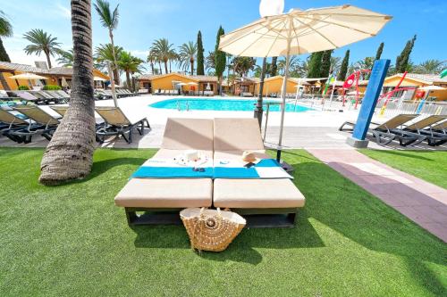 una panchina con ombrellone accanto alla piscina di Suites & Villas by Dunas a Maspalomas
