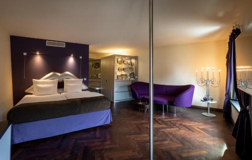 a hotel room with a bed and a purple couch at ARCOTEL Onyx Hamburg in Hamburg