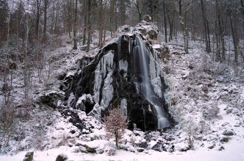 a waterfall is covered in snow in a forest at FeWo Robin in Bad Harzburg