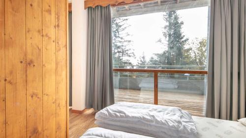 une chambre avec un lit et une grande fenêtre dans l'établissement V du Bachat Silenes B11 Appt belle vue 4 6 pers, à Chamrousse