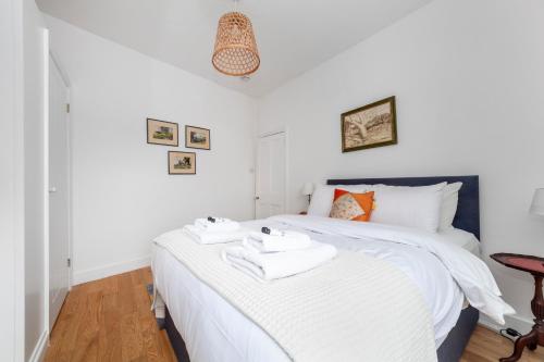 a bedroom with a white bed with towels on it at Stylish 3 BDR apartment wfree parking and garden in Kingston upon Thames
