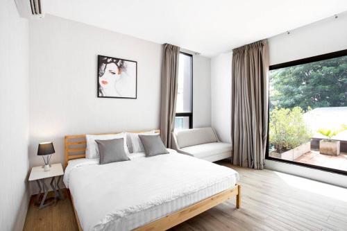 ein weißes Schlafzimmer mit einem Bett und einem großen Fenster in der Unterkunft Bangkok Luxury Pool Villa Thonglor in Bangkok