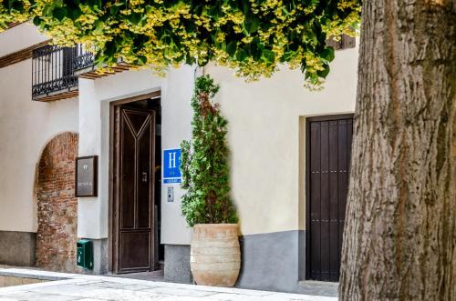 un edificio con una puerta y un árbol en YIT Abentofail, en Guadix