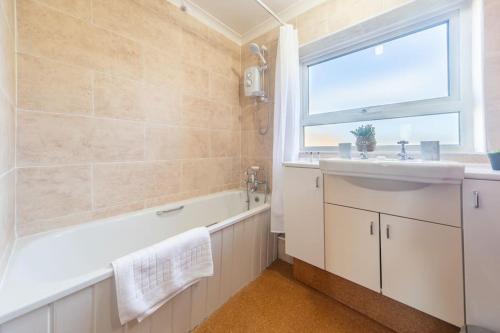 un bagno con lavandino, vasca e finestra di Charming 4-Bedroom House-York a Stockton on the forest